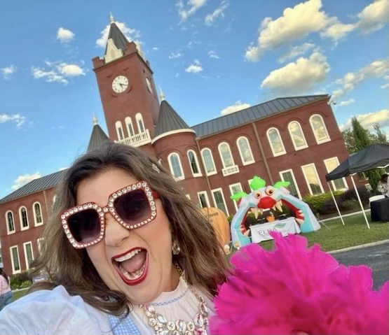 Marilyn Chivetta takes a selfie in the town square adorned with sparkly sunglasses and a pink boa