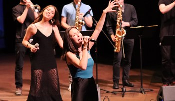 Anna Colson singing into a microphone during a performance