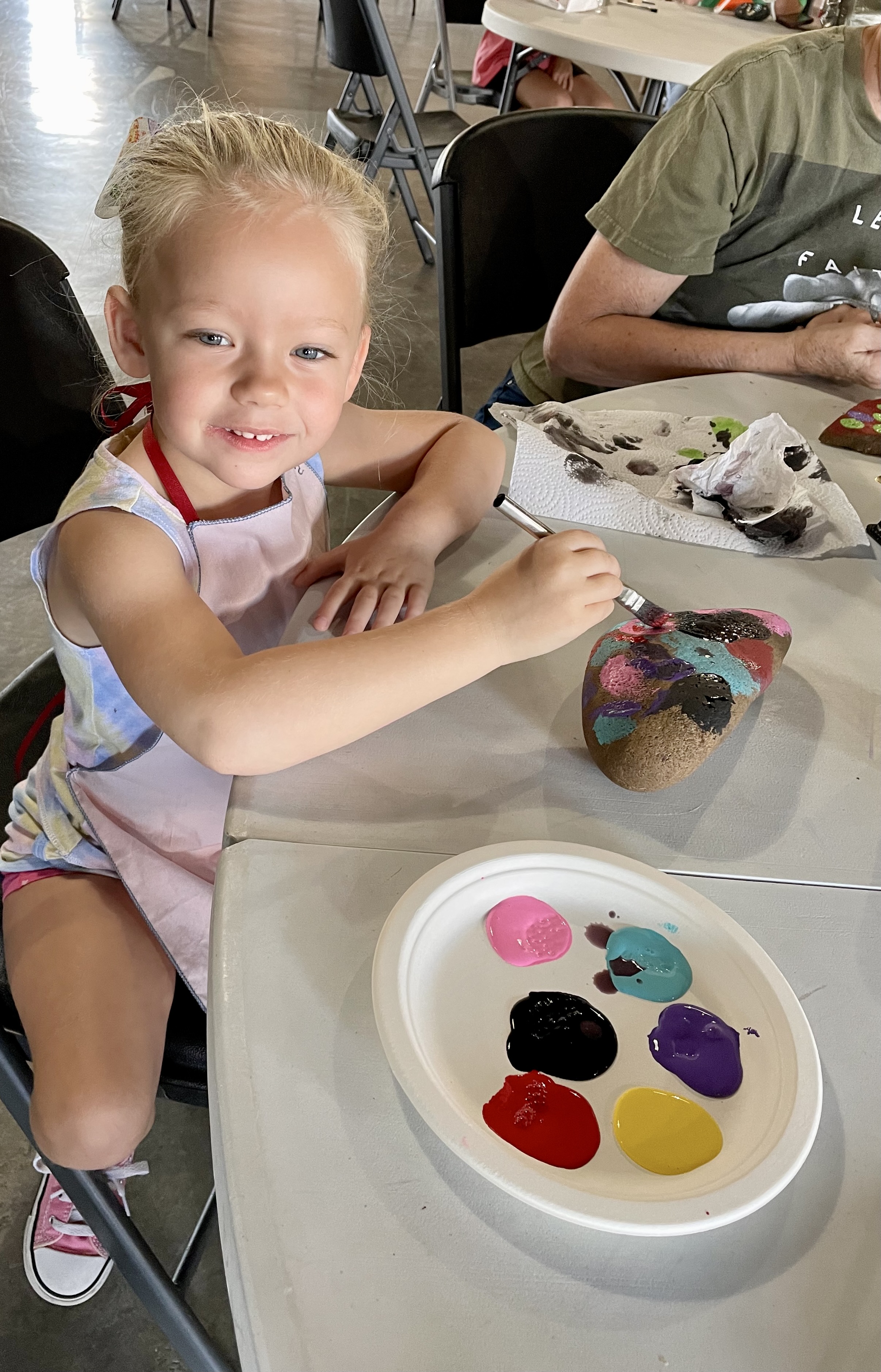 a child sits at a table with a plate dotted with different paint colors