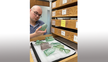 Nickolas Long examining broken bottles on a lab table