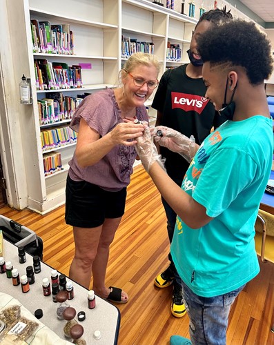 Kristin Law helps two students pick essential oils for soap fragrances