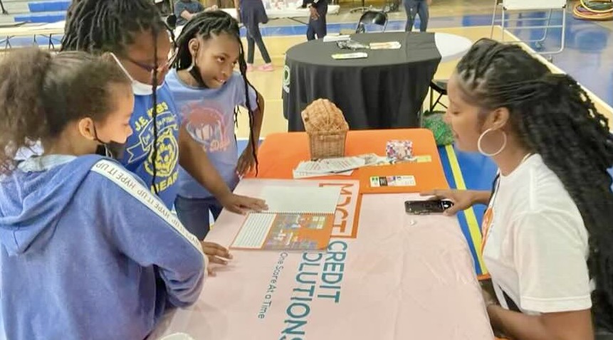 Iesha Smith gathers children at a table to discuss financial literacy