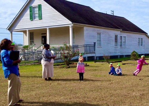 Children play in front of an old house that serves as a museum