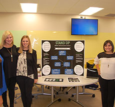 students standing around a presentation board in a classroom