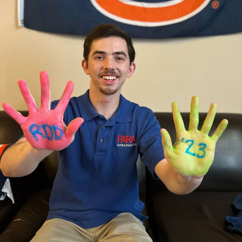 Noah Griffith wears a FARA ambassador shirt and holds up his hands painted to read RDD 23