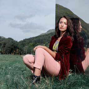 Gabrielle Bates in grassy field posing next to mirror