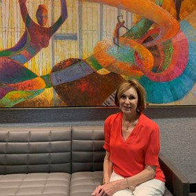 Laura Lewis sits in front of her mural at the Gogue Performing Arts Center