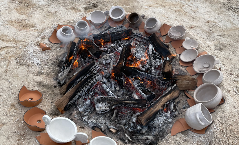 Image of the coals of a fire surrounded by clay pots 