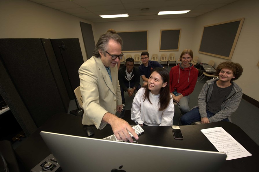 Professor teaching students around a computer screen