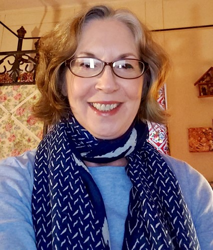 Robin Rowan smiles behind her glasses and blue scarf