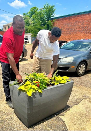 Two men add fresh plants to the new planters in downtown Camden