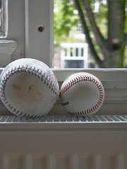two baseballs sit on a window silll
