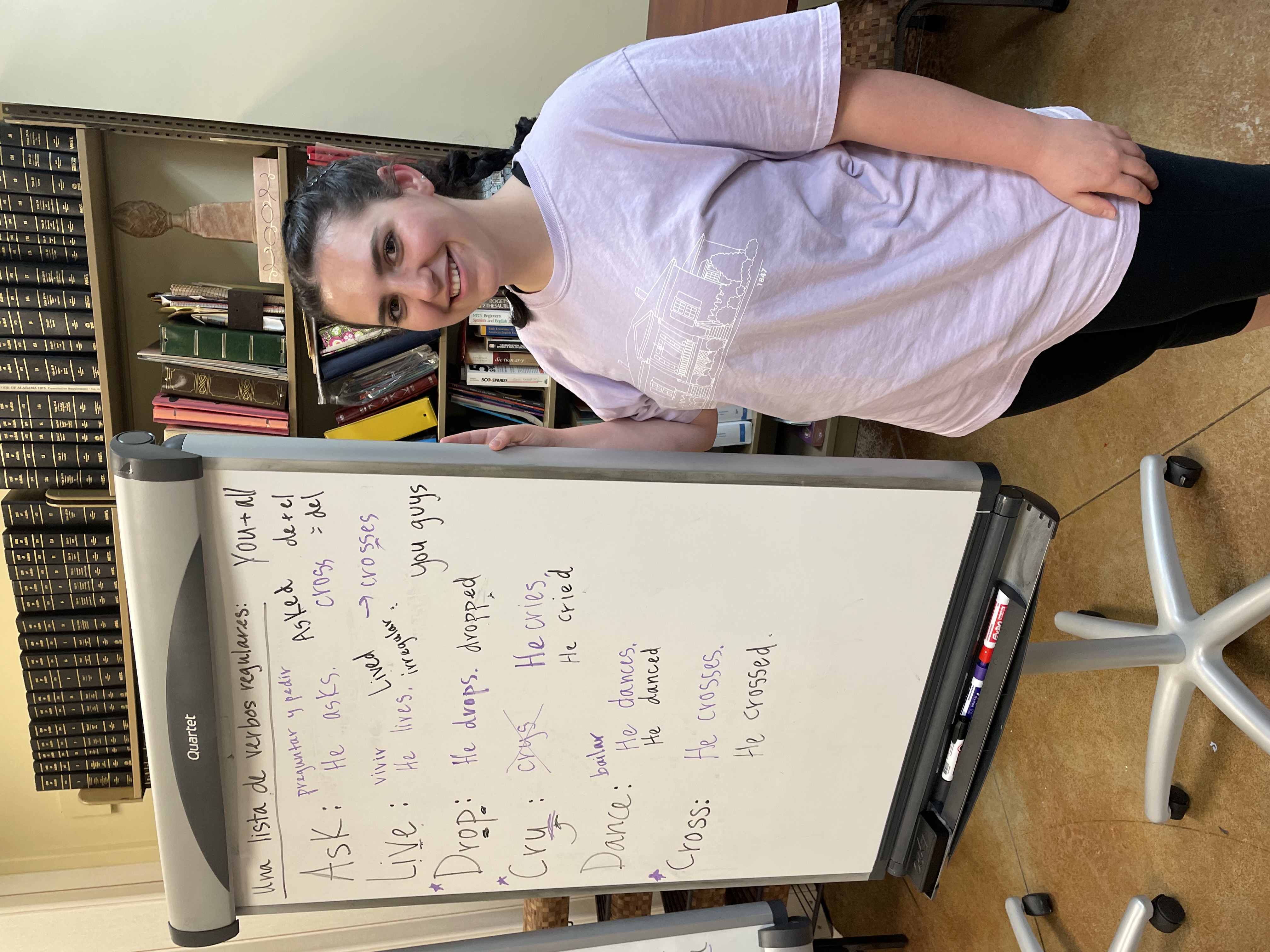 Payton stands at a white board covered with Spanish to English translations for an ESL class