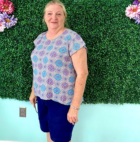 Donna Falls, director of Elba Senior Center, poses in front of boxwood wall at the senior center.