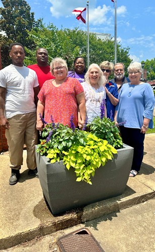 Community members stand with pride in front of freshly placed planters in downtown Camden