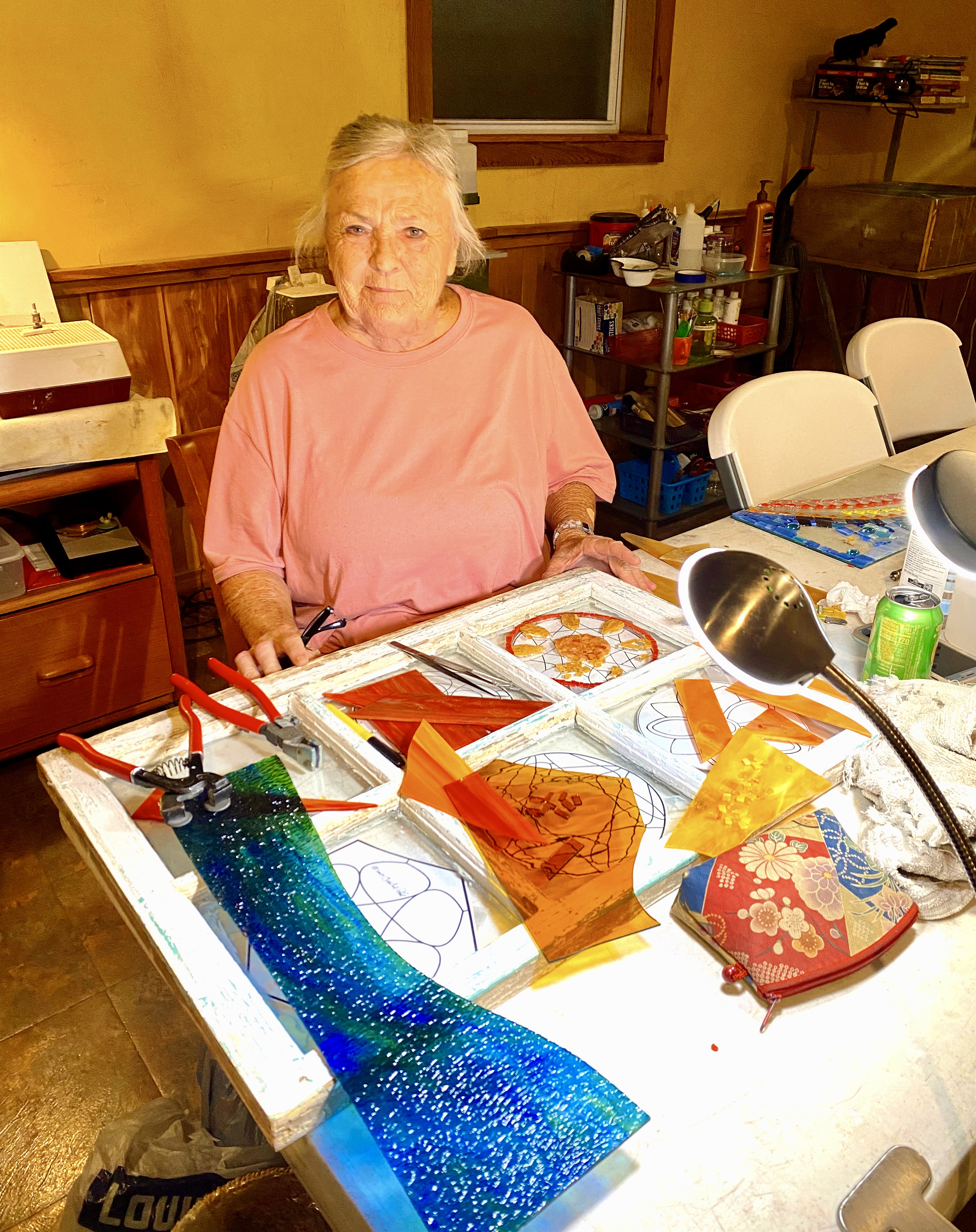 woman sitting at table creating stained glass art