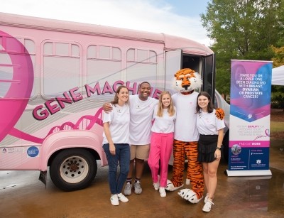 People standing in front of pink Gene Machine bus