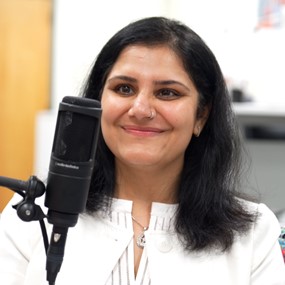 Dr. Gargi Sawhney sits behind a microphone while recording a podcast