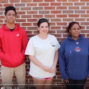 three students standing in front of a brick wall